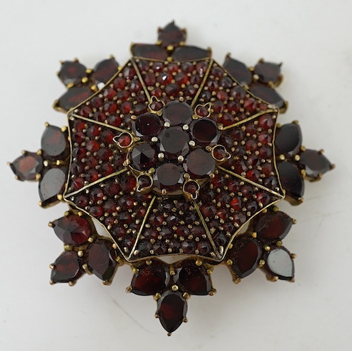 A Victorian style yellow metal and garnet cluster set snow flake brooch, 41mm. Condition - fair